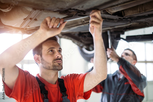 Car mechanics working at automotive service center © NDABCREATIVITY