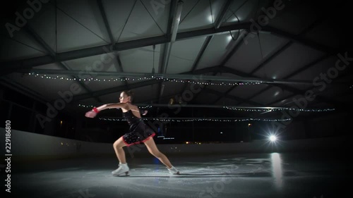 A figure skater prepares to start spinning on the ice. She spins very elegantly.