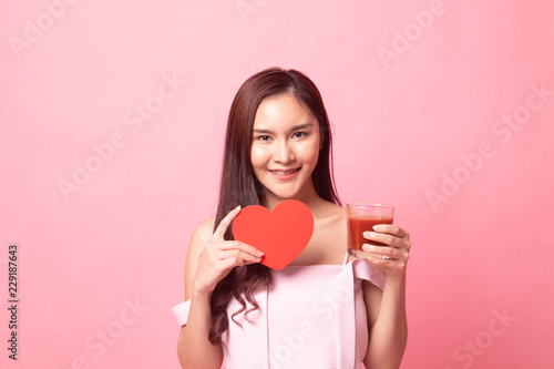 Young Asian woman with tomato juice and red heart .