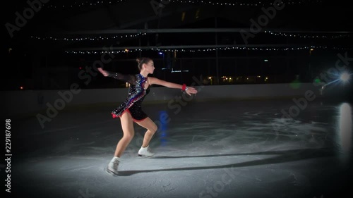 This beautiful figure skater performs so beautifully in the ice rink. photo