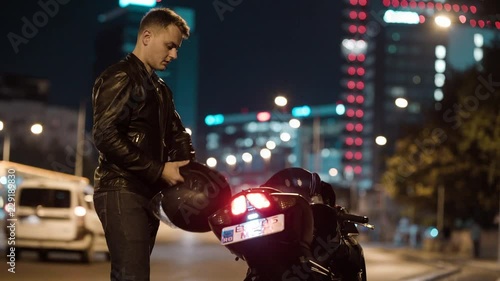 Man walking motorcycle putting on helmet gloves getting on bike night city traffic street blur cinematic photo