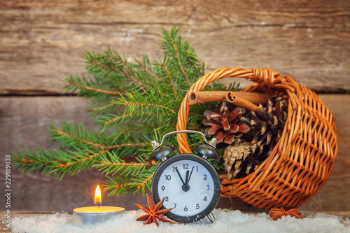 Christmas New Year composition winter objects fir branch basket pine cones candle alarm clock on old rustic wooden background. Xmas holiday december decoration copy space. Time for celebration concept