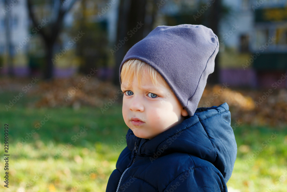 Sad boy in hat outdoor. Autumn shoot. Cute toddler profile portrait. Copy space Sad boy in hat outdoor. Autumn shoot. Cute toddler profile portrait. Copy space