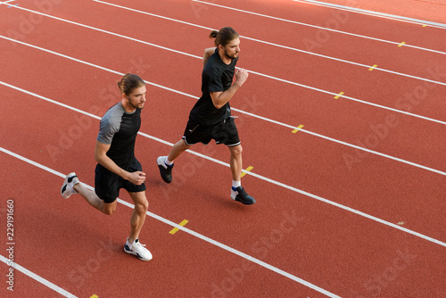 Two twins sportsmen brothers running at the stadium outdoors.