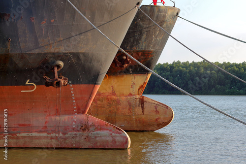 Prows of two old rusty ships with anchor chain anchored at Danube river at summer photo