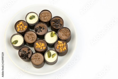 Chocolate candy on a white plate. Sweet beautiful candy lying on a plate on a bright color background. © ALEXEY