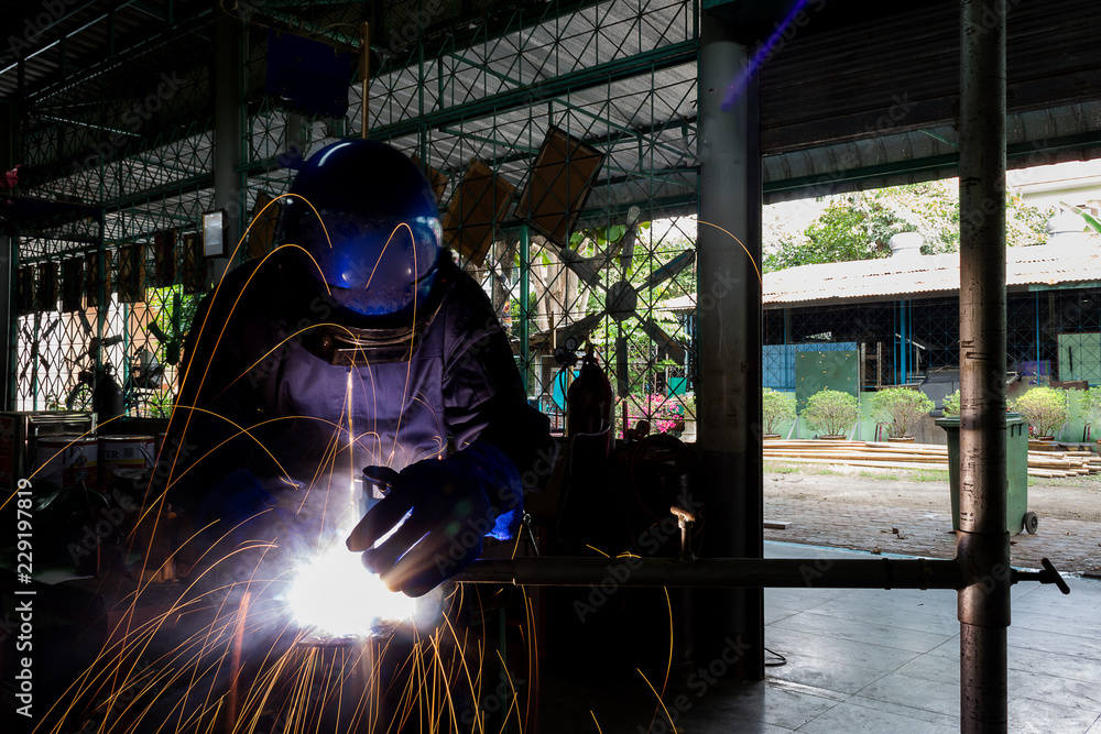 Working person About welder steel Using electric welding machine There are lines of light coming out and safety equipment. Working person About welder steel Using electric welding machine There are lines of light coming out and safety equipment.