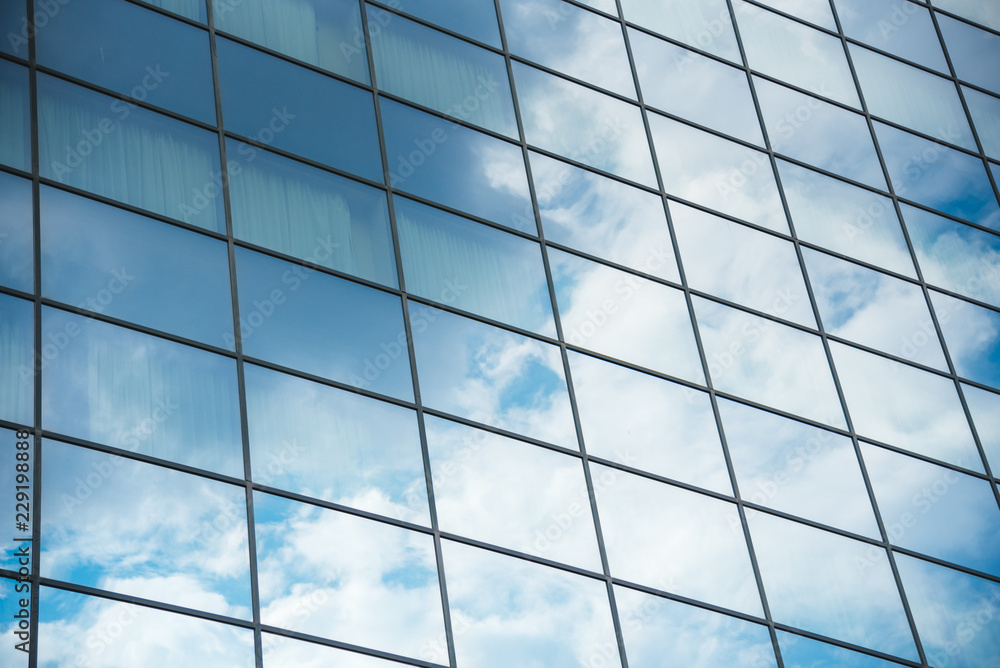 Glass corporate building with glass windows during the day. Sky reflections in the windows Glass corporate building with glass windows during the day. Sky reflections in the windows