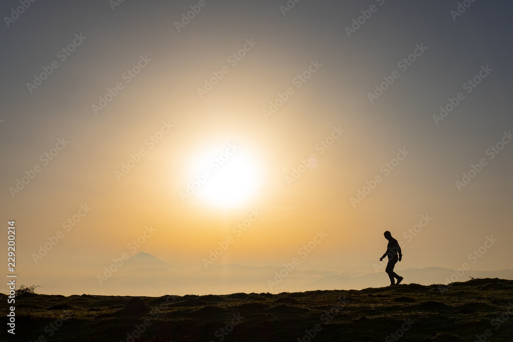 Man on the top of the hill watching wonderful scenery of colorful sunrise in mountains of Basque Country