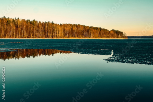 Beautiful autumn landscape. The first ice on a forest lake in the sunset. photo