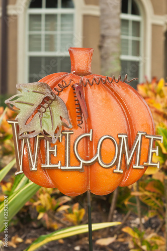 Front view, close distance of a metal cut out display of a pumpkin and a sign of welcome of the frot garden of a tropical residence on a sunny, autumn day photo