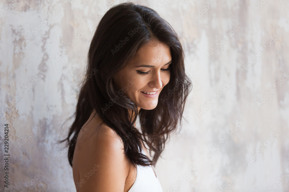 Young brunette woman shyly smiles and looks down Young brunette woman shyly smiles and looks down