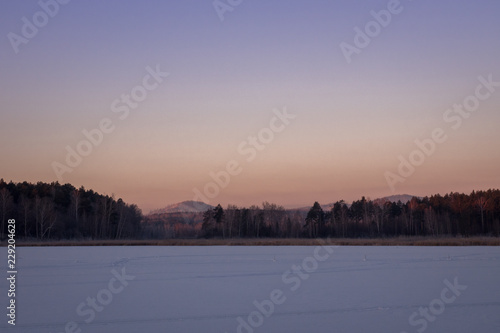 beautiful sunset on a mountain lake. frosty snow day winter.