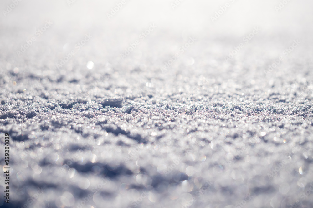 Macro shot of pure white snow with shallow depth of field and pleasant blurry bokeh. Great winter christmas background for your layout