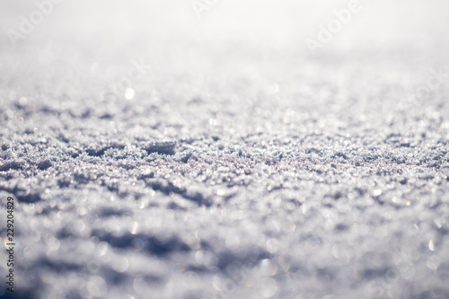 Macro shot of pure white snow with shallow depth of field and pleasant blurry bokeh. Great winter christmas background for your layout