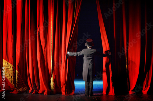 Fotografía Actor in a tuxedo and hat looks behind the theater curtain