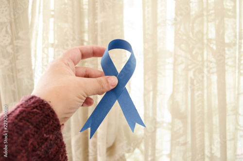 woman hand holding blue ribbon, blue november conceot photo