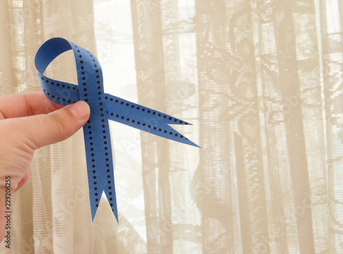 woman hand holding blue ribbon, blue november conceot photo