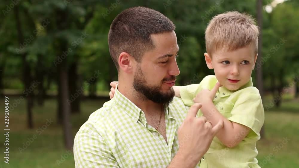 Portrait of a happy bearded father with his son in the Park in the summer. Father and son play in the summer Park in warm Sunny weather. Close-up. Slow motion. Portrait of a happy bearded father with his son in the Park in the summer. Father and son play in the summer Park in warm Sunny weather. Close-up. Slow motion.