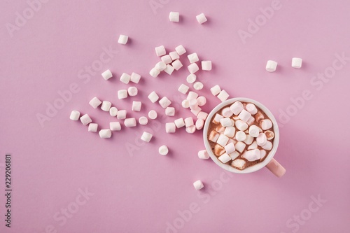 Top view of white and pink marshmallows in mug on pink background