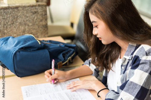 Young woman writing a travel registration form on the table.