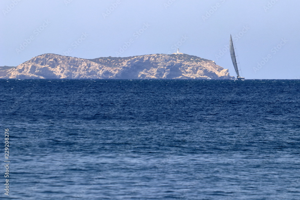 Barca a vela nel vento in vista di terra