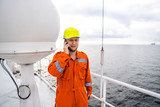 Marine Deck Officer or seaman on deck of vessel or ship . He is speaking on the mobile cell phone