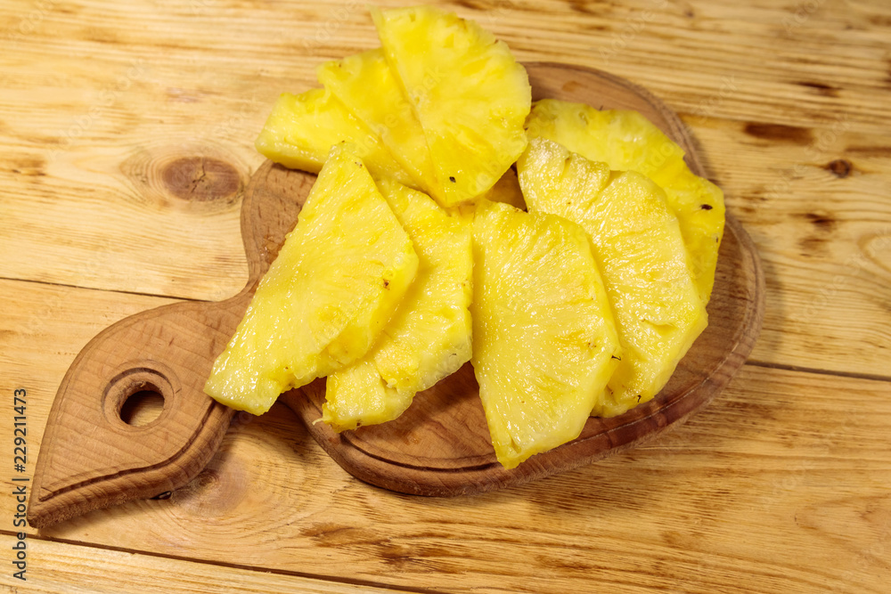 Pieces of pineapple on a cutting board on wooden table. Top view Pieces of pineapple on a cutting board on wooden table. Top view