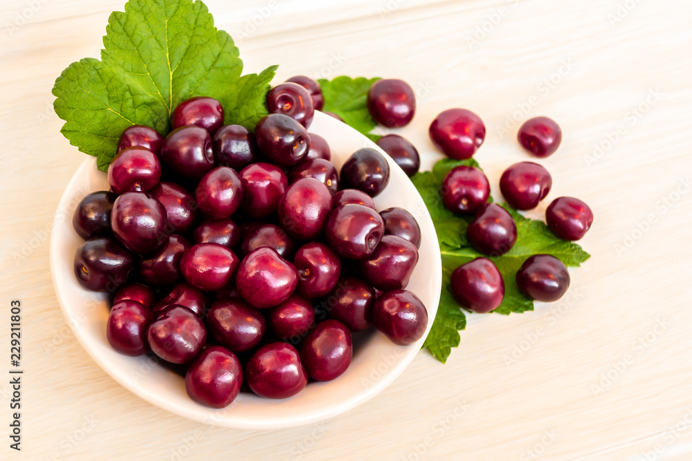 Fresh ripe sweet cherry in a plate on a light table