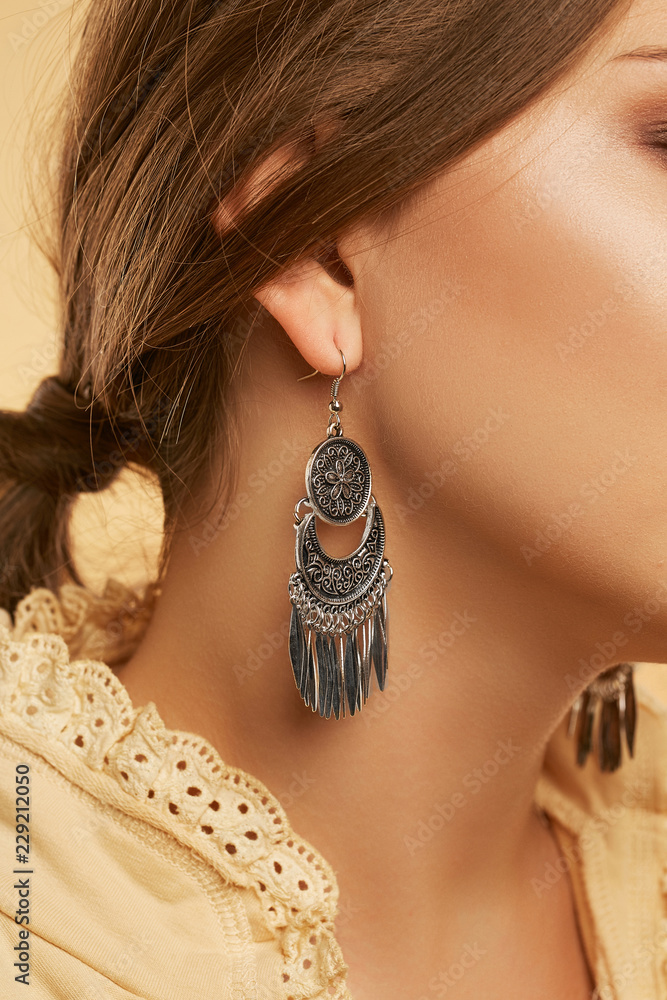 A close up shot of oxidized silver Chandbali earring hanging from woman's  earlobe. Cropped portrait of the brunette lady with low ponytail hairstyle,  smooth skin. Ethnic Indian fashion accessories. Stock-Foto | Adobe
