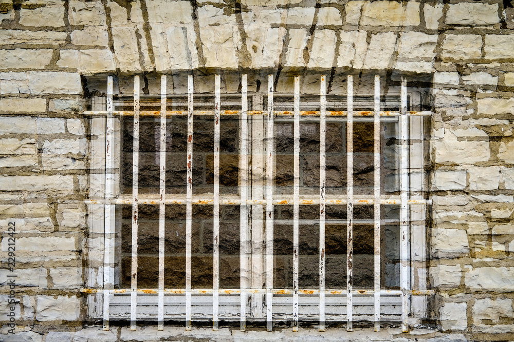 Obraz premium old jail window in limestone wall