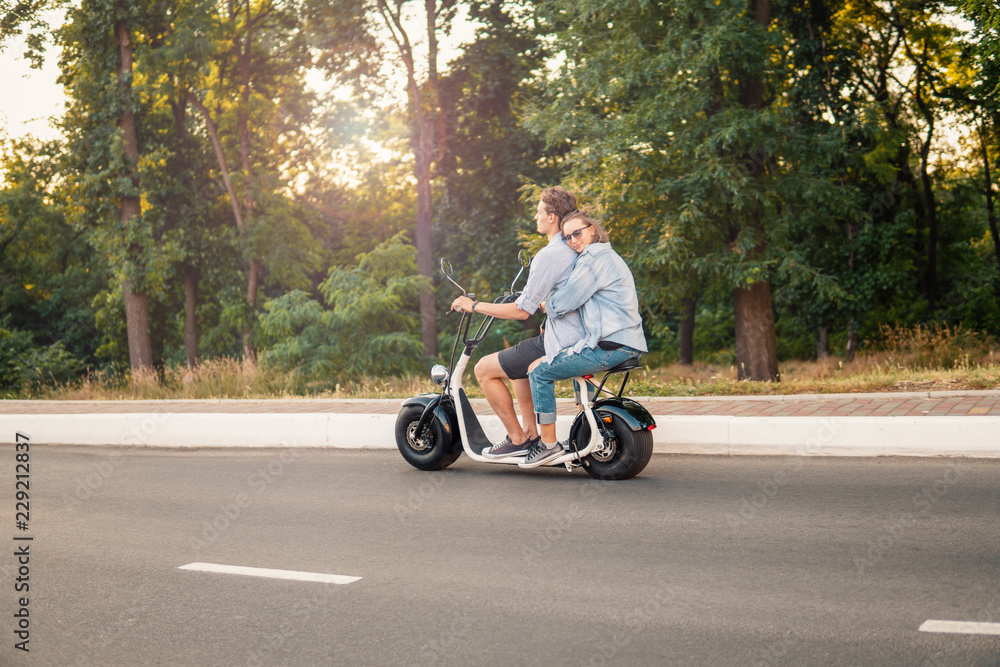 Lovely young couple driving electric bike during summer Modern city life and transportation Lovely young couple driving electric bike during summer Modern city life and transportation