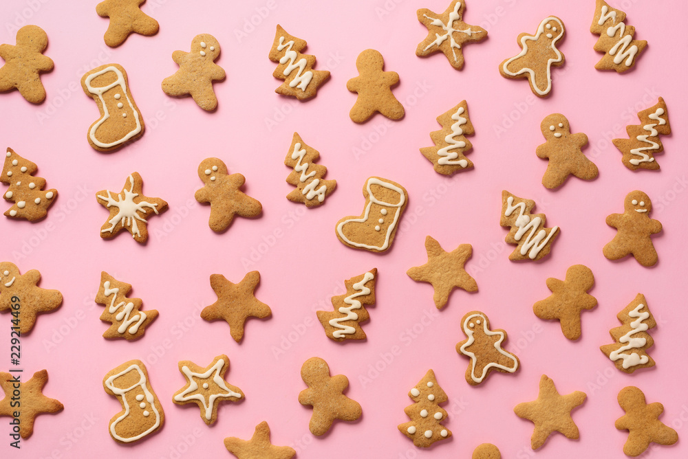 Christmas handmade cookies on pink background. Pattern of gingerbread men, snowflake, star, fir-tree, boot shapes. New year concept
