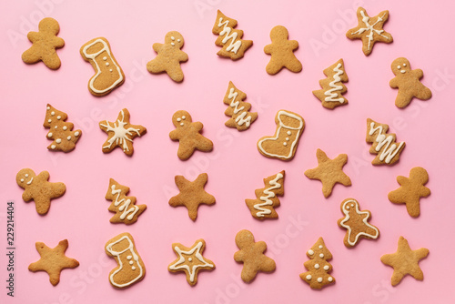 Homemade christmas cookies on pink background. Pattern of gingerbread men, snowflake, star, fir-tree, boot shapes. New year concept