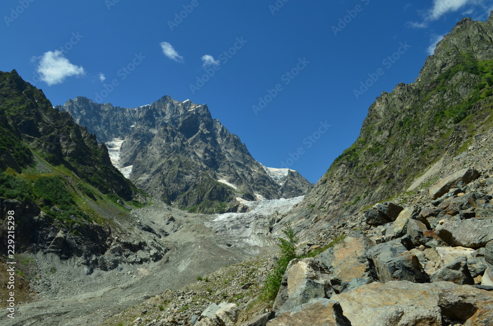  huge glacier and green mountains and boulders in the foreground