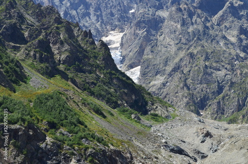 steep green mountain and rock with a glacier in the background