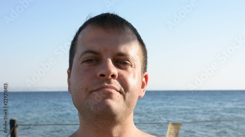 Young fat man drinking beer and eatsfast food near the sea photo