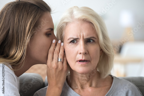 Quadro em tela Young woman whisper in aged mother ear sharing secret or hidden information, sur