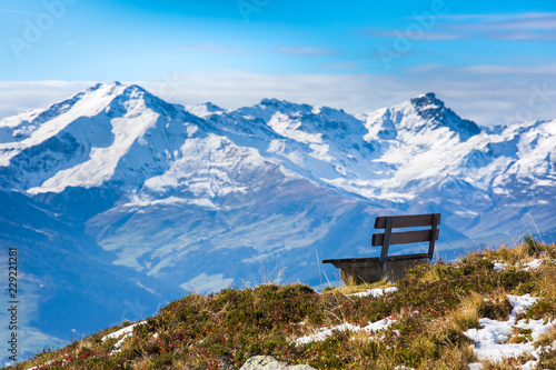 Beautiful view with lonely bench on the top of Mayrhofen ski resort with snow covered mountains on the background