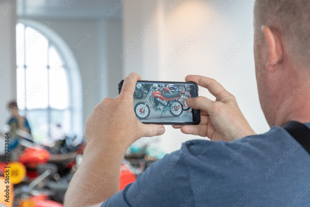 A young man photographed on the phone motorcycles in the Museum. Rear view. A young man photographed on the phone motorcycles in the Museum. Rear view.