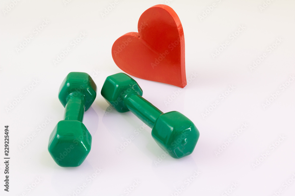 Two green dumbbells for exercising and a red heart white background Two green dumbbells for exercising and a red heart white background