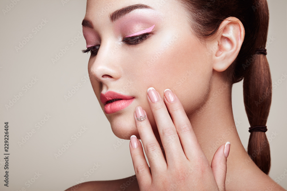 Fototapeta premium Beauty brunette woman with perfect makeup. Red lips and nails. Perfect eyebrows. Skin care foundation. Beauty girls face isolated on beige background. Fashion photo