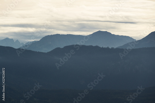 Mountain silhouettes with forest and cloudy sky © Patrick