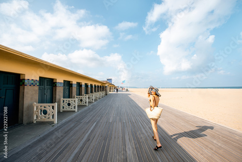 Woman walking on the beach with locker rooms in Deauville, famous french resort in Normandy. Wide angle view