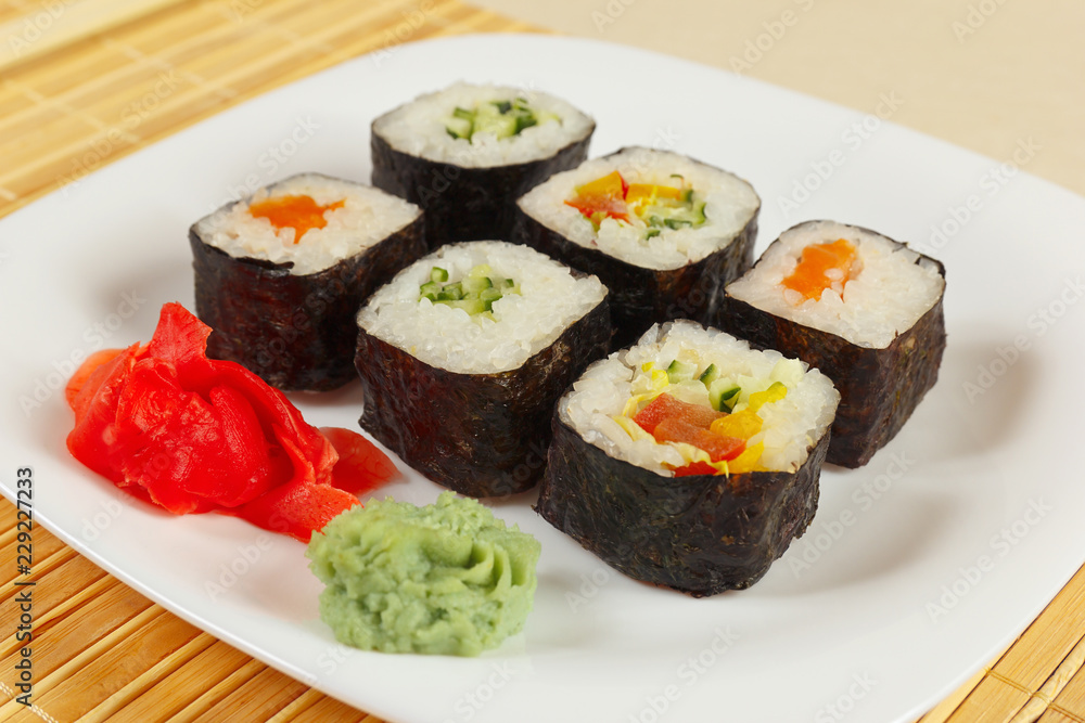 Assorted sushi with ginger and wasabi on a bamboo mat close up.