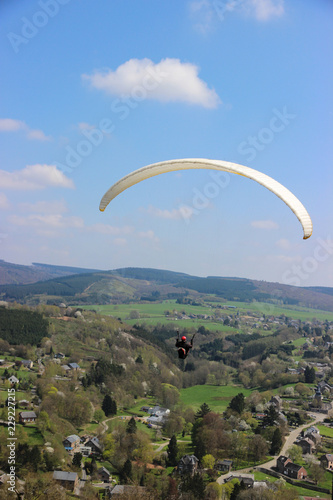 Paraglider flying in the sky over a small village