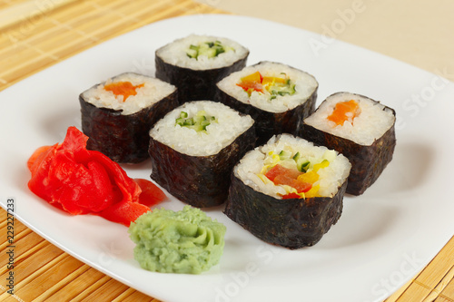 Assorted sushi with ginger and wasabi on a bamboo mat close up.