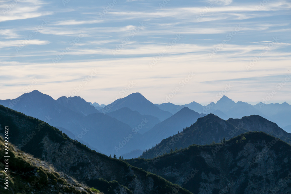 Naklejka premium Mountain silhouettes with forest and cloudy sky