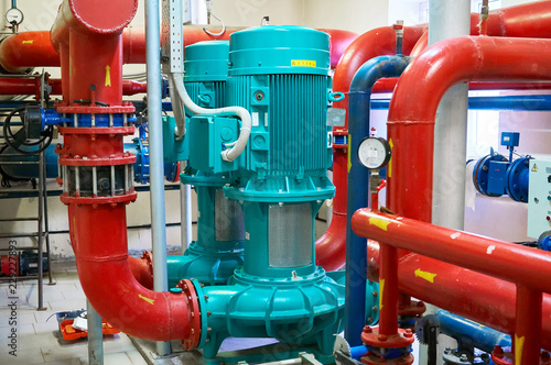 Two vertical engines painted blue with pumps connected to pipes painted red.