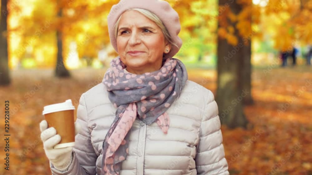 old age, retirement and people concept - close up of happy senior woman walking along autumn park and drinking takeaway coffee old age, retirement and people concept - close up of happy senior woman walking along autumn park and drinking takeaway coffee